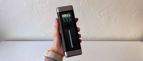 The CUKTECH 20 portable charger in someone&#039;s hand in front of a white table