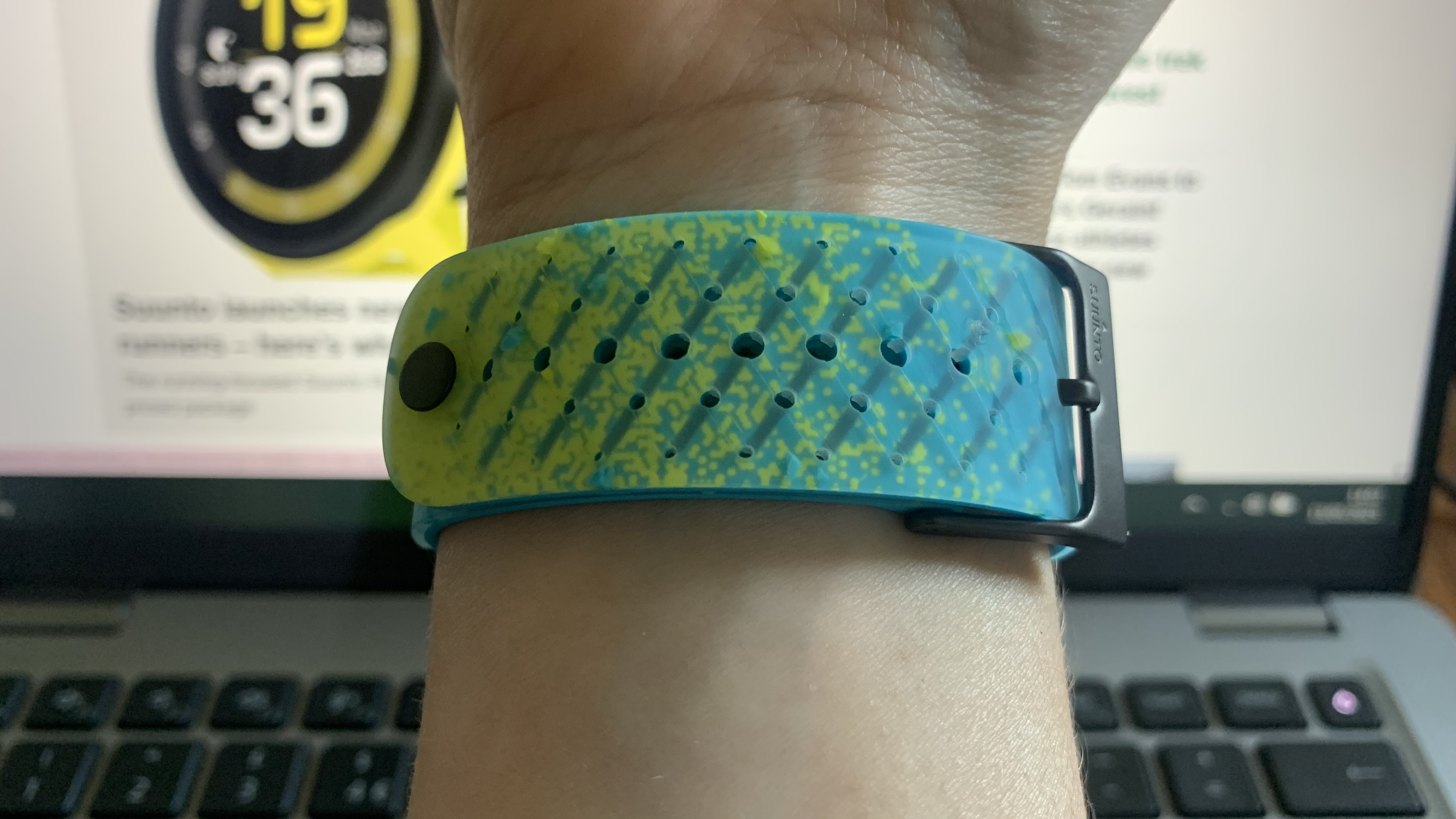 Image shows the fastening on the Suunto Race S watch with laptop in background