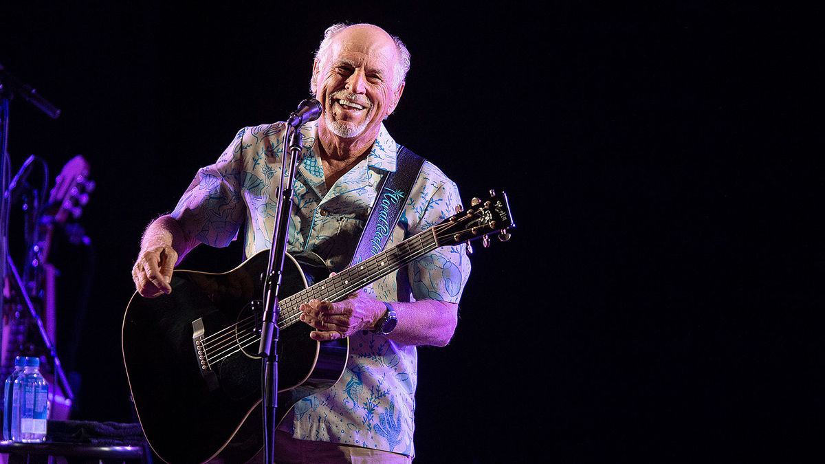 Jimmy Buffett playing guitar onstage in 2021