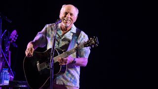 Jimmy Buffett playing guitar onstage in 2021