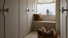 A neutral minimalist linen closet with a bay window and a basket with pillows