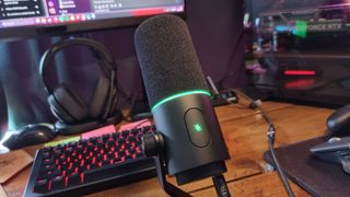 A Razer Seiren V3 Pro microphone on a desk, in front of a gaming keyboard