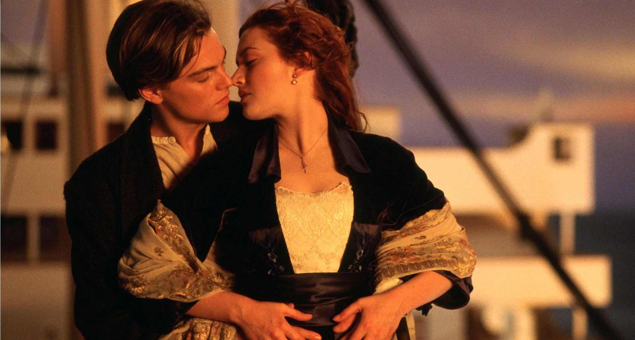 leonardo dicaprio as jack embracing kate winslet as rose from behind on the head of a ship in a still from the movie titanic