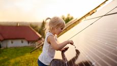 A little girl examines a solar panel.