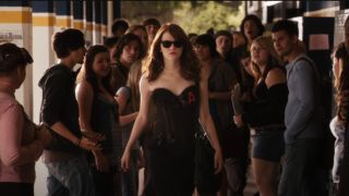Emma Stone walking down in the hall in an outfit with an A on it.