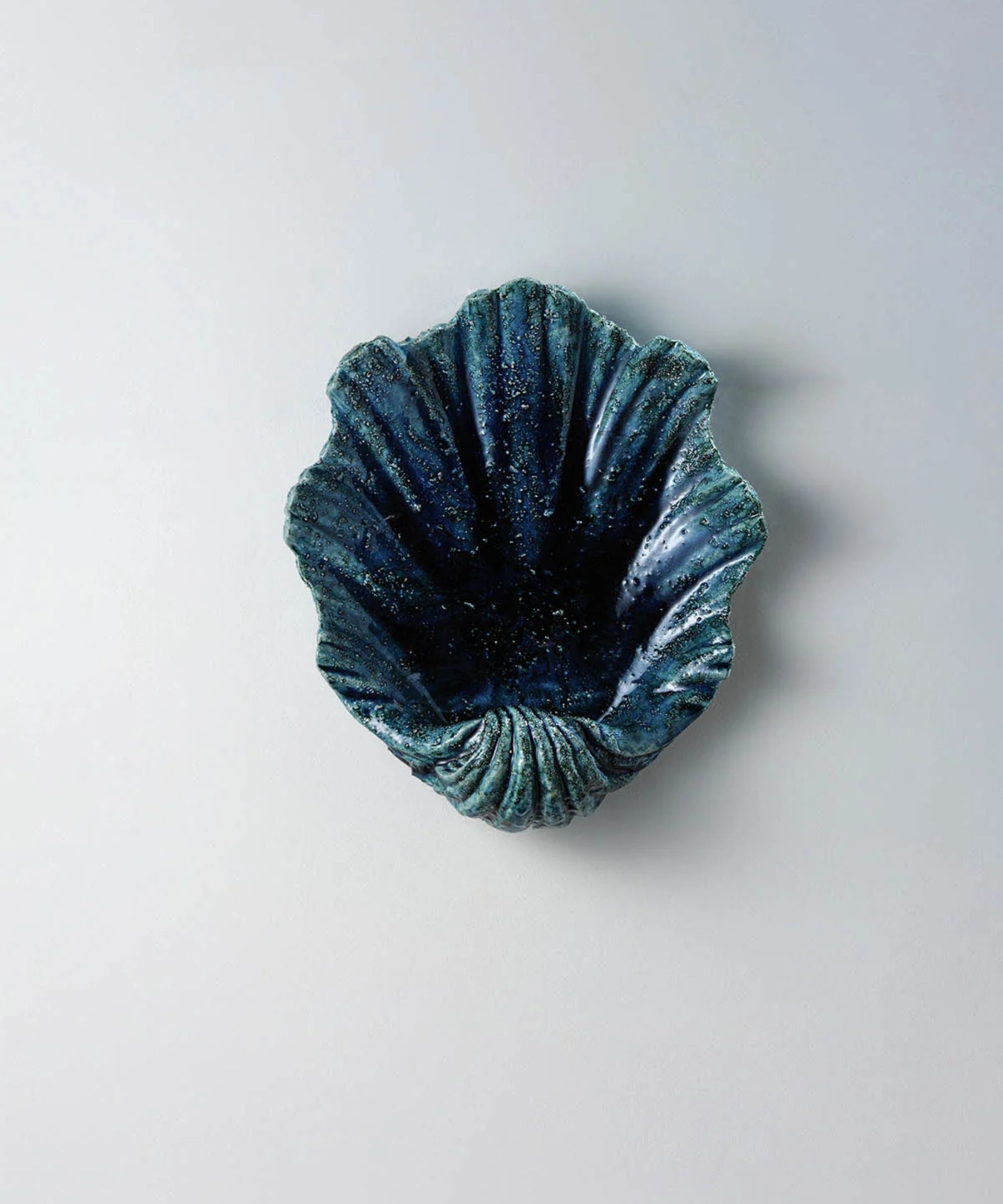 A blue wall sconce in the shape of a shell