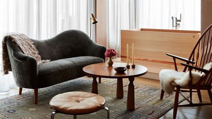 bathroom with timber tub, green rug, lounge, table and armchair