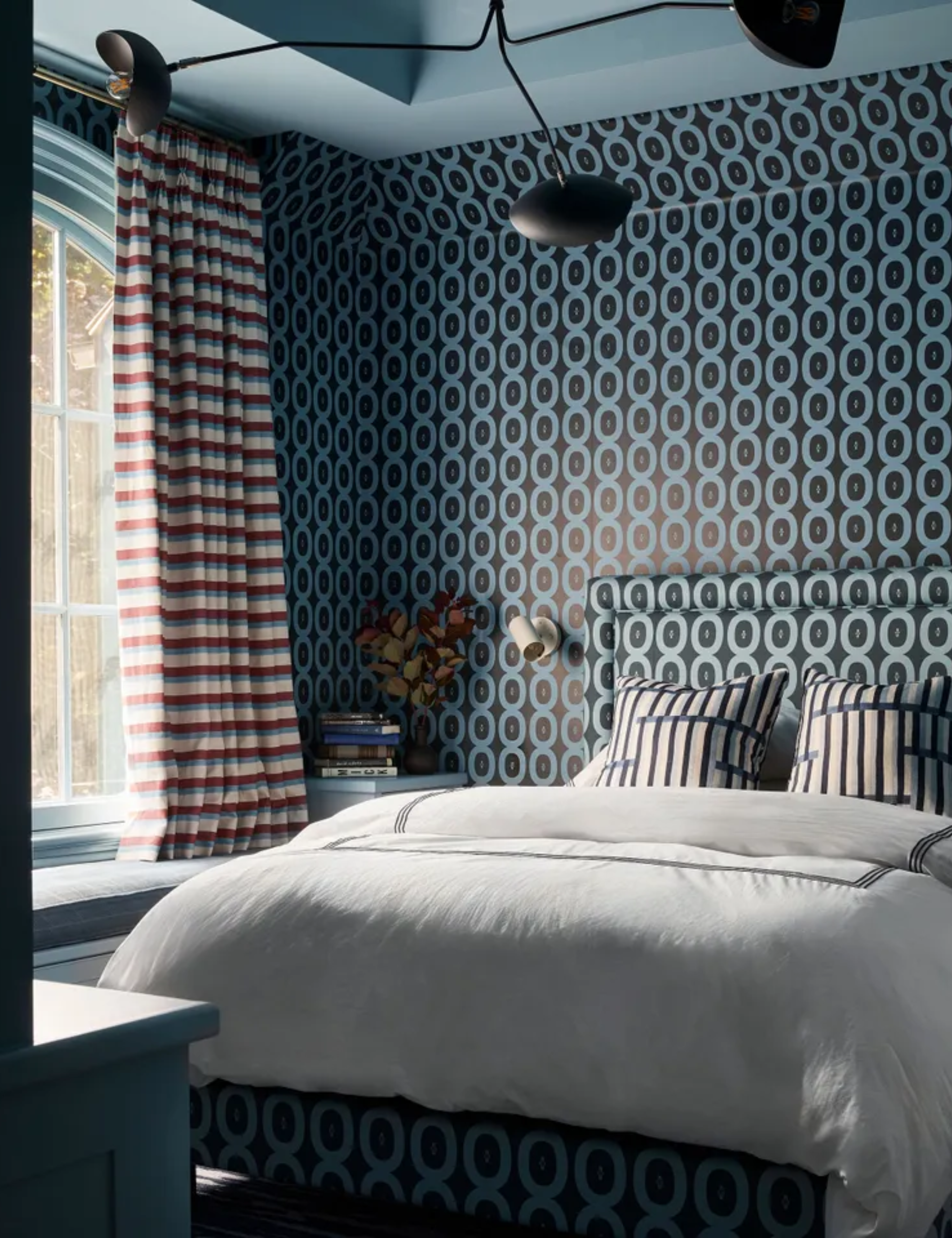 A teenage son's bedroom with a graphic blue pattern of circular motifs across the walls, and also covering the headboard.