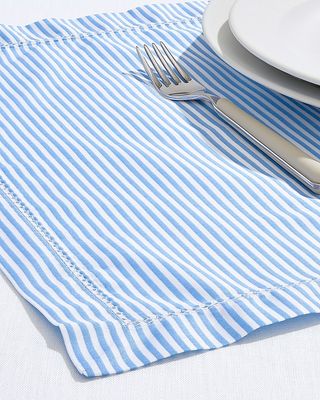 blue and white striped placemat with cutlery and the edge of a plate on top
