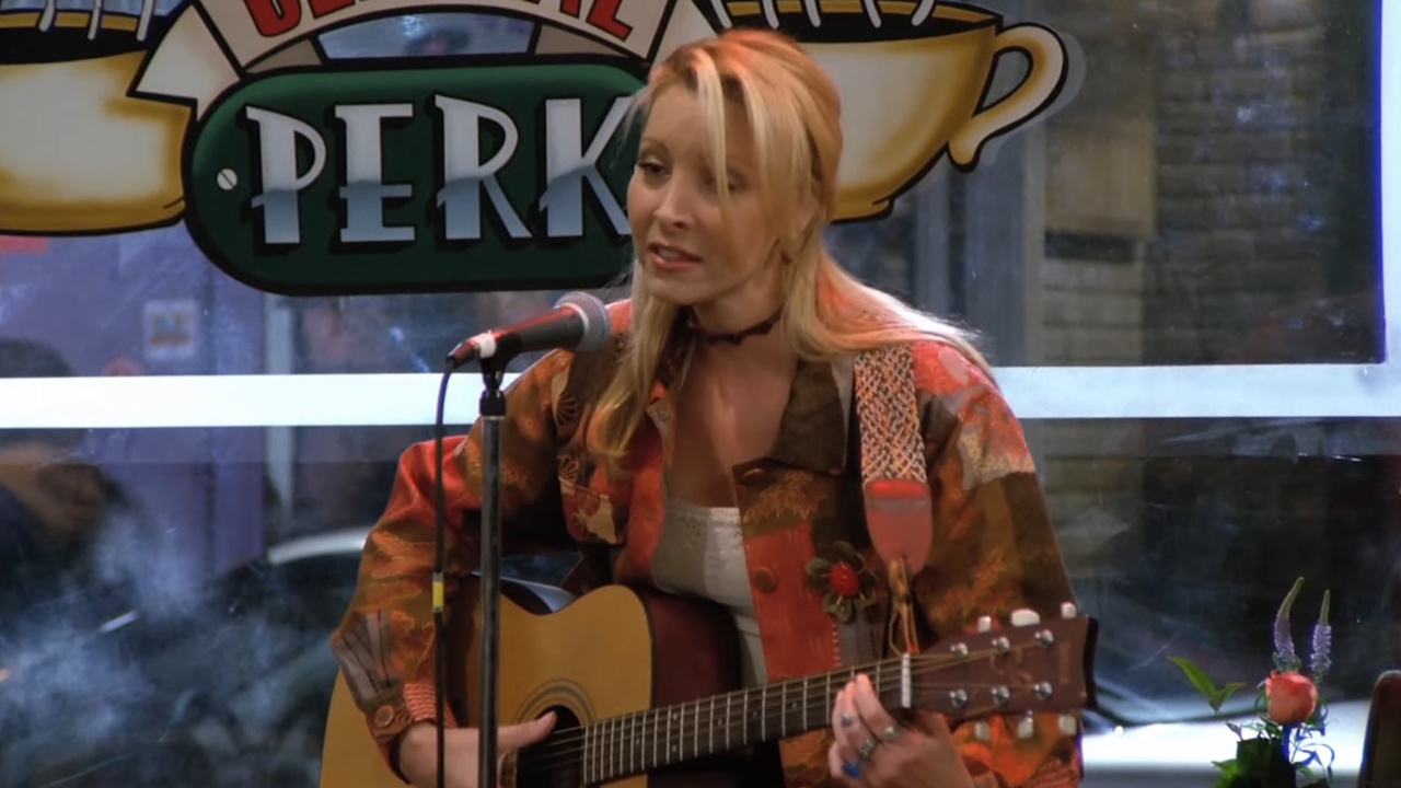 Phoebe (Lisa Kudrow) plays guitar at Central Perk.