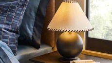 Studio McGee Threshold collection whipstitch lampshade and sculptural lamp base sitting bedside on a wooden table