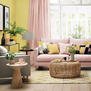 yellow walled living room with pink sofa and wooden flooring