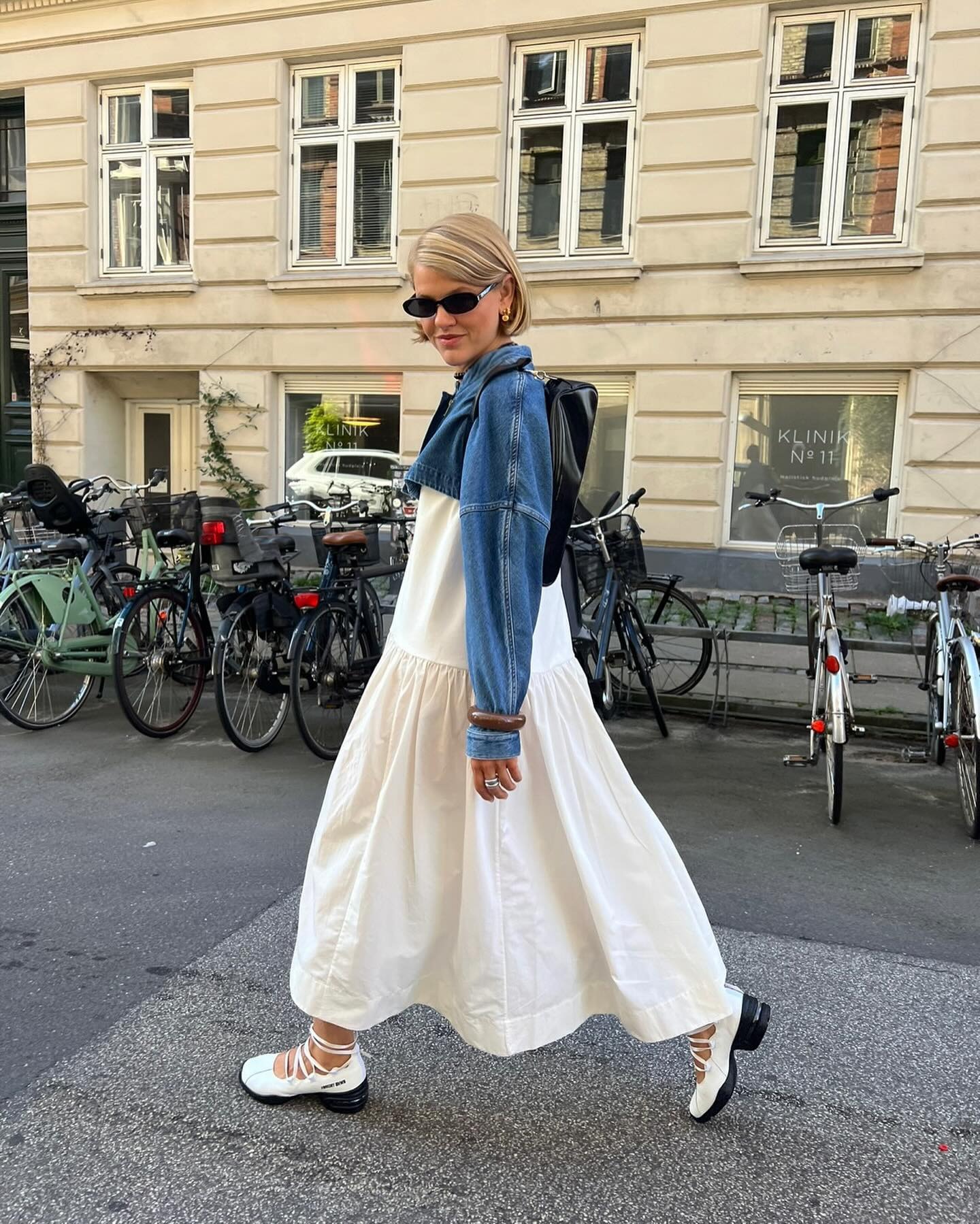 Fashion person Amalie Nielsenn @amalienielsenn wears a leather trainer outfit 2026. She wears Sneakerina trainers with a maxi dress and denim jacket.