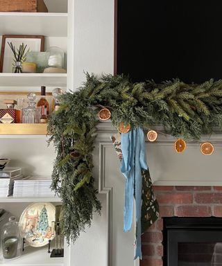 traditional brick and wooden fireplace in a neutral living room with a foliage and dried orange garland