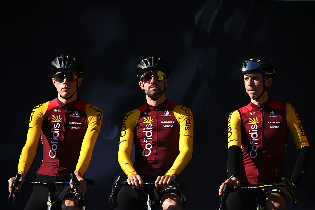 Three Cofidis riders against a moody, dark background