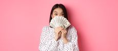 money saving apps - portrait of woman holding paper currency against pink background