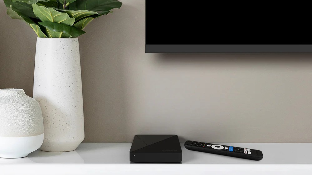 Google TV Streaming Box 260 PRO (4K) box and remote next to a TV