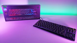 Razer Huntsman V3 Pro Low-Profile Tenkeyless 8KHz gaming keyboard sitting in front of its retail box under purple studio light.