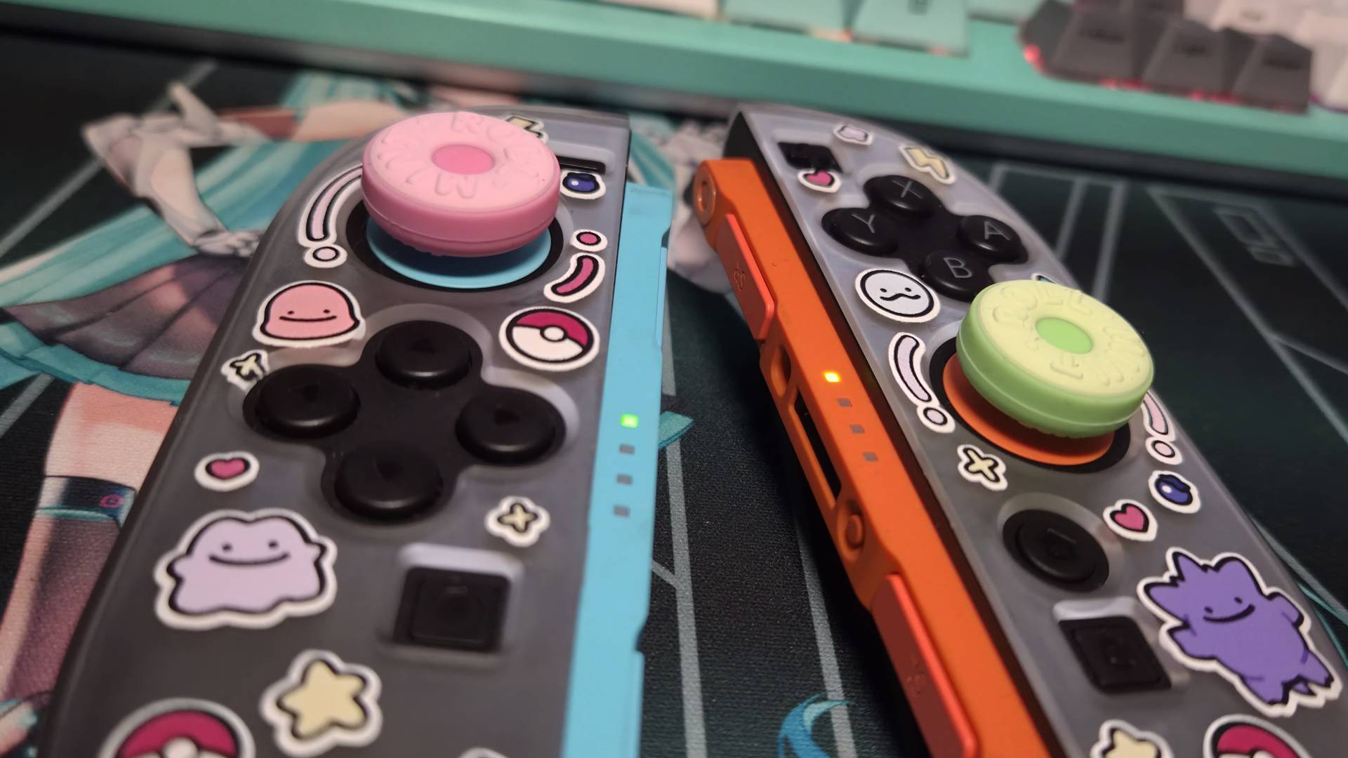 Photo of a pair of grip covered Switch 2 Joy-Con controllers sitting on a Hatsune Miku desk mat.
