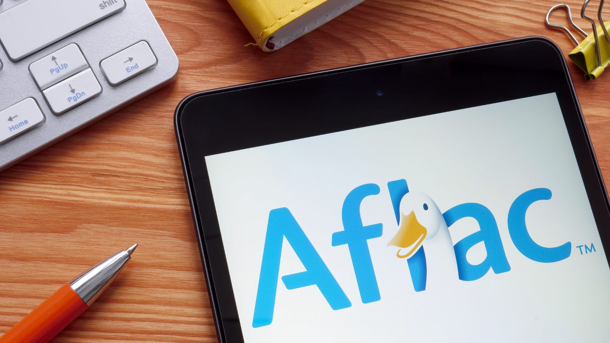 Aflac logo on phone sitting on a desk next to pen and keyboard 