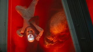 The Distortus Rex holds an upside down technician against a window in Jurassic World Rebirth.