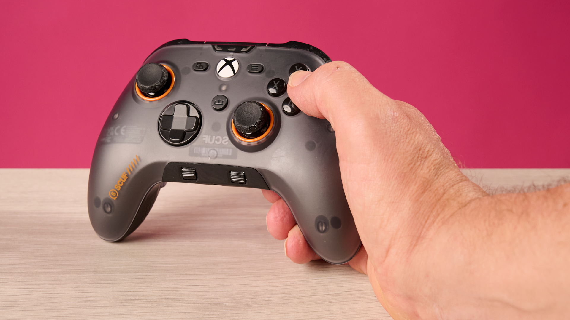 A man's handing holding the Scuf Valor Wired with TMR and pressing the B button.