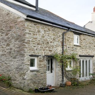house with stone wall and white door and windows