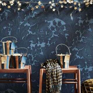 metallic buckets on wooden benches in front of blue patterned wallpaper