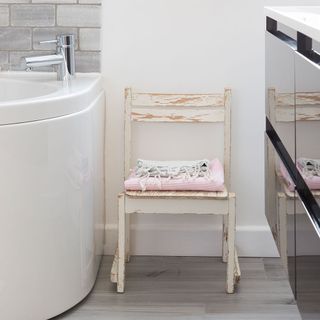 bathroom with white wall grey designed flooring and wooden chair