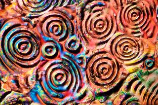 This image of aspirin crystals was created using pure aspirin powder melted on a microscope slide. Once it is liquid, a thin slip is slid over the top of the aspirin, which forms these intriguing circular shapes. Vivid colors are created by the use of cro