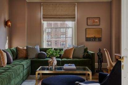 A living room with olive sofa and pink walls