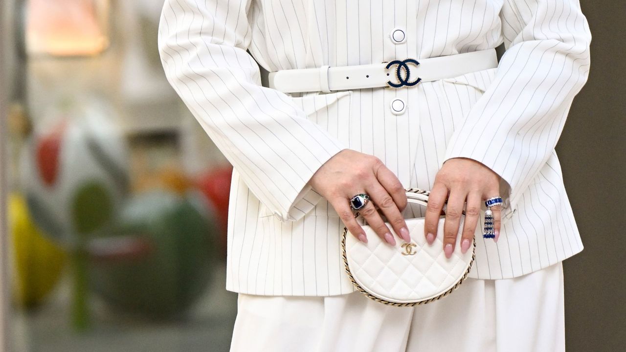 A close up of a woman&#039;s nails holding on to a chanel handbag - How to make your manicure last longer