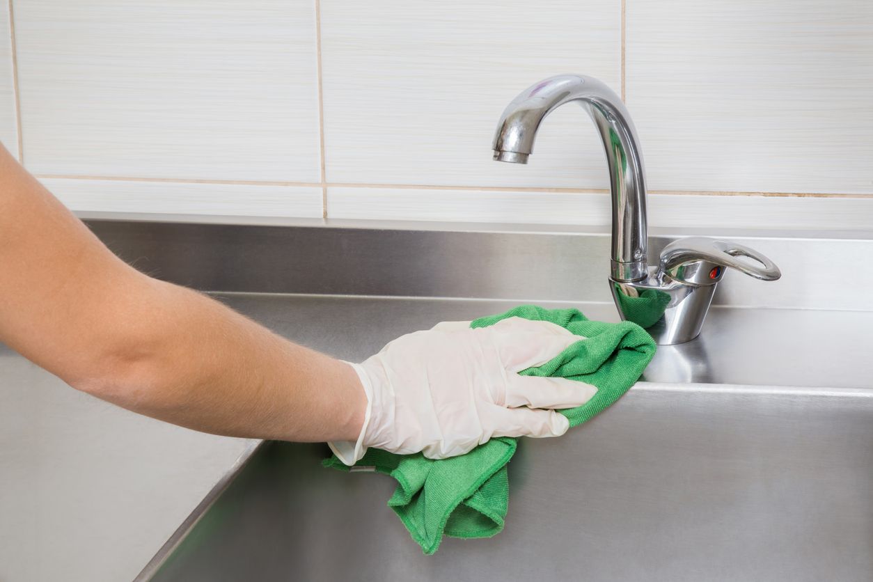 A person cleans a stainless steel surface.