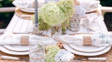 Rattan tableware laid out on an outdoor table with hydrangeas