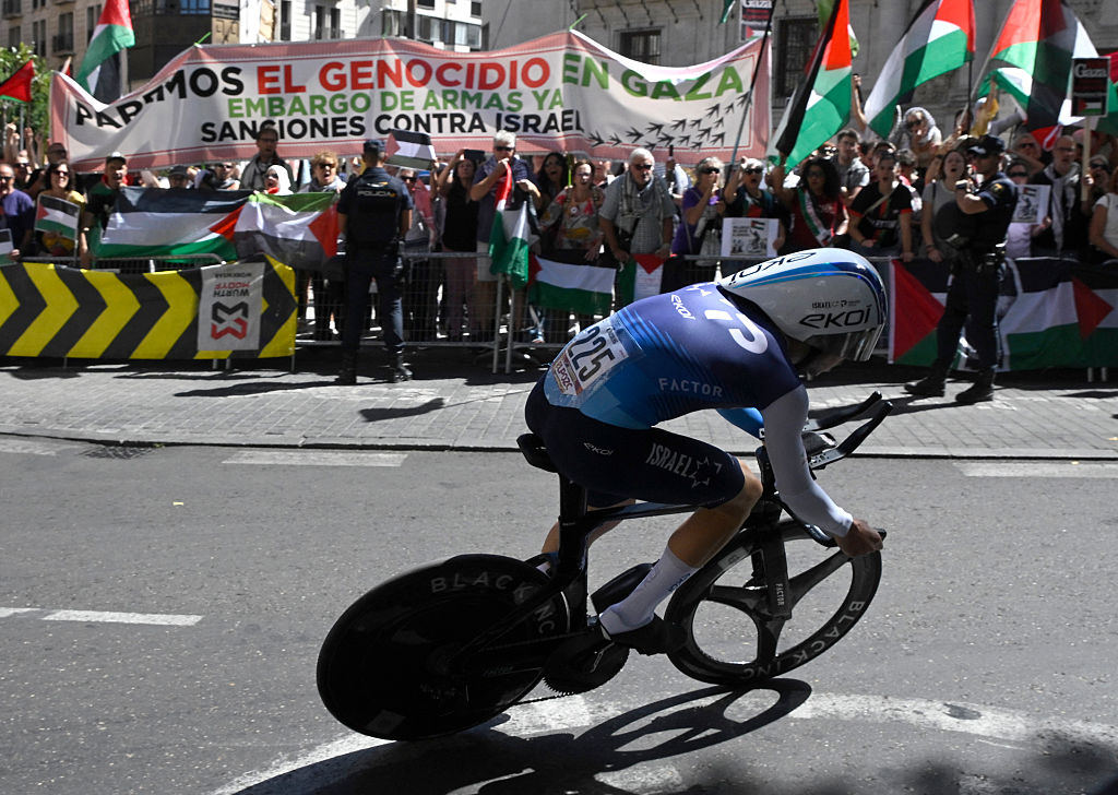 Pro-Palestinians protesters wave Palestinian flags as Team Israel Premier Tech&#039;s Israeli rider Nadav Raisberg competes during the 18th stage of the Vuelta a Espana, a 26 km race against the clock between Valladolid and Valladolid, on September 11, 2025. (Photo by Miguel RIOPA / AFP)
