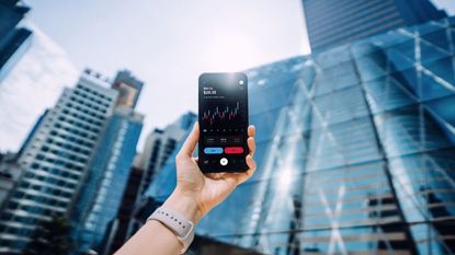 hand holding up a smartphone with stock market analysis on mobile app