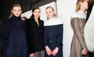 Models wear navy and black teddy coats, another wears a shirt dress in navy and white