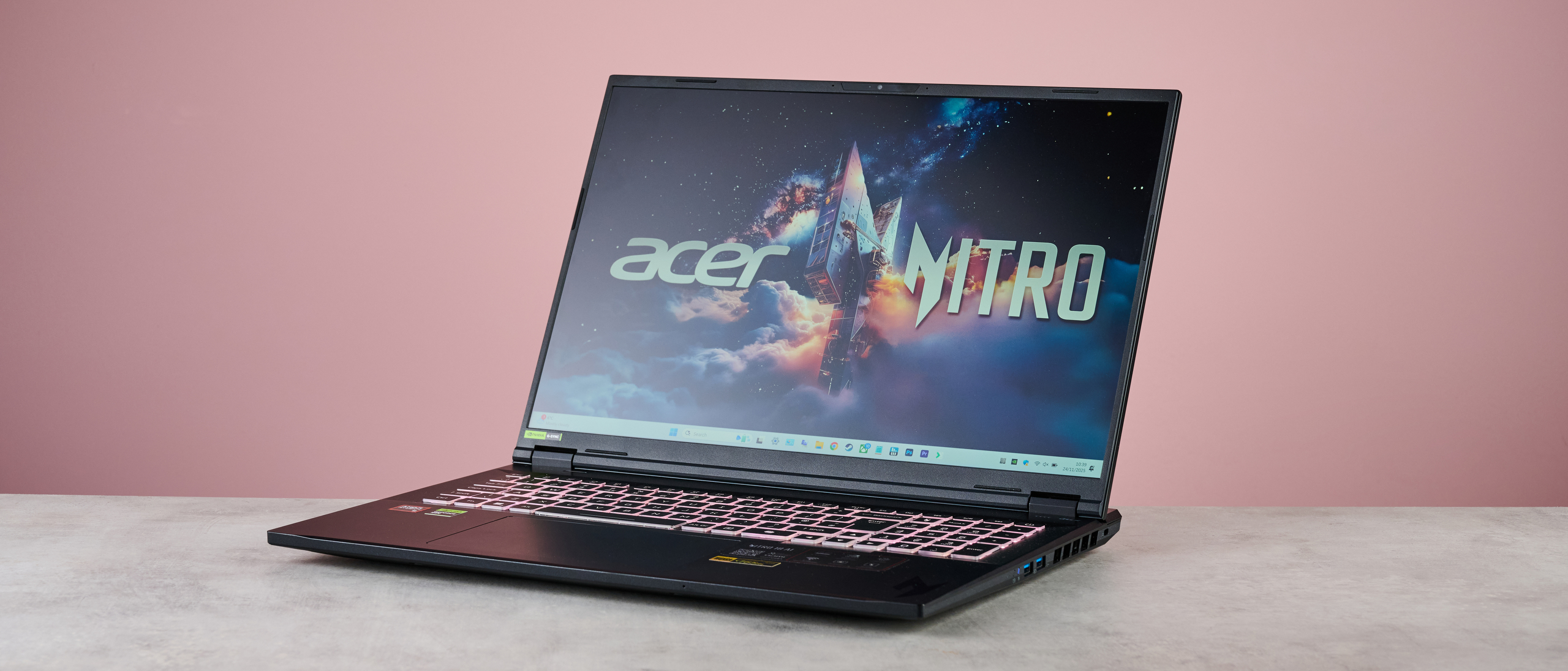 Three-quarter view of Acer Nitro 18 AI open on desk, with pink wall in background