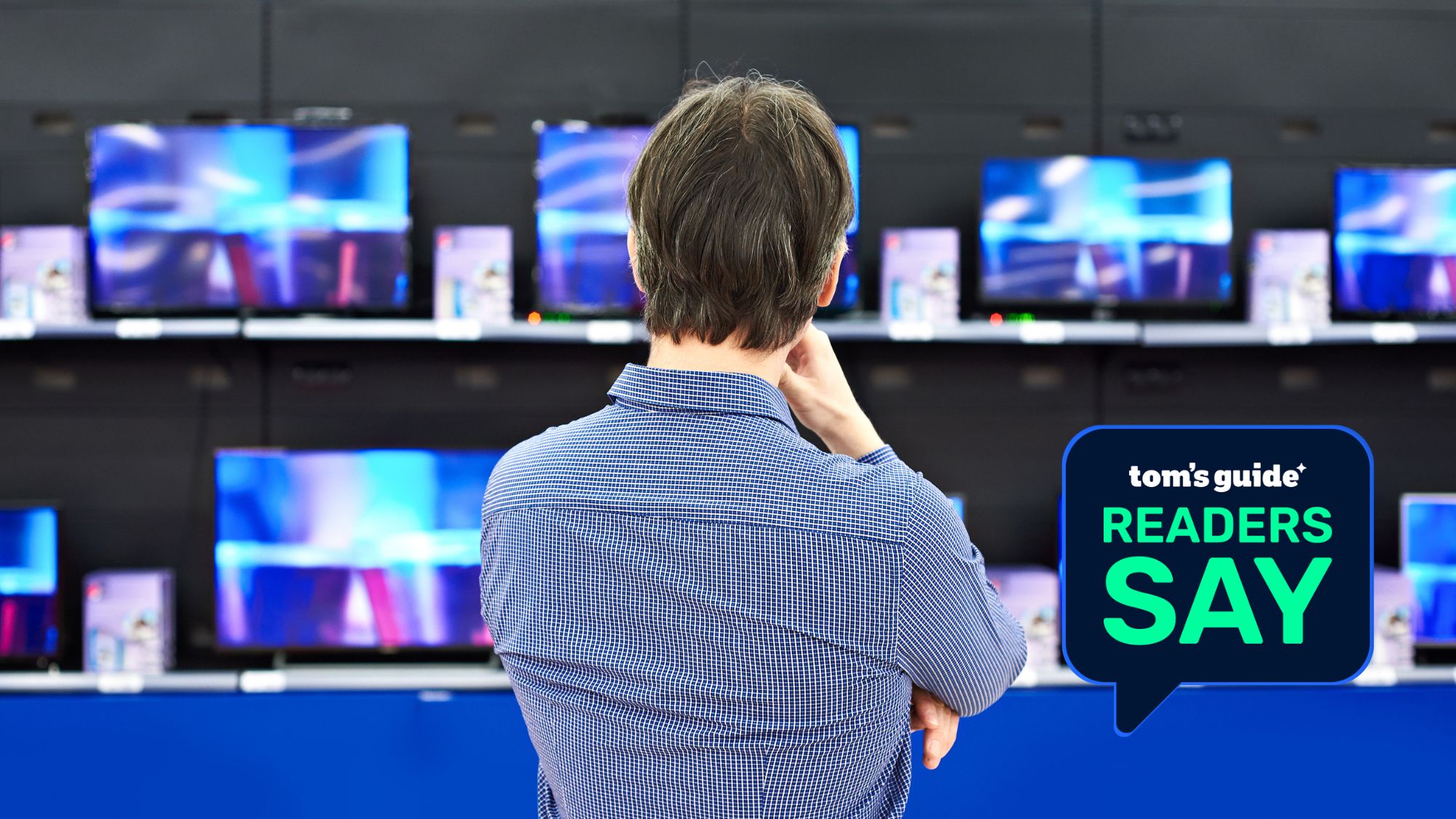 A man thoughtfully looks at LCD TVs in a large store with his back to the camera