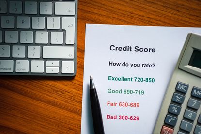 Example credit score thresholds on a sheet of paper with a calculator and laptop