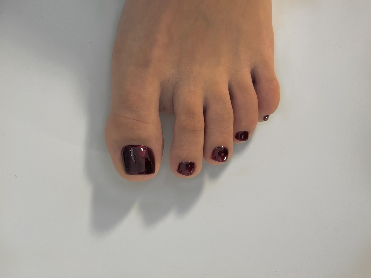 A pedicure with a dark shimmery red nail polish