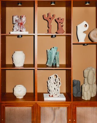 A vibrantly decorated design showroom and concept store features a bookshelf filled with sculptural artworks.