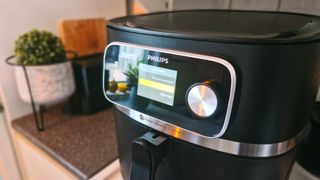 En Philips 7000 XXL står på en köksbänk med skärmen aktiv och visar menyn över förinställda program.