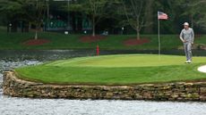 Hunter Mahan walks on an island green with an American flag