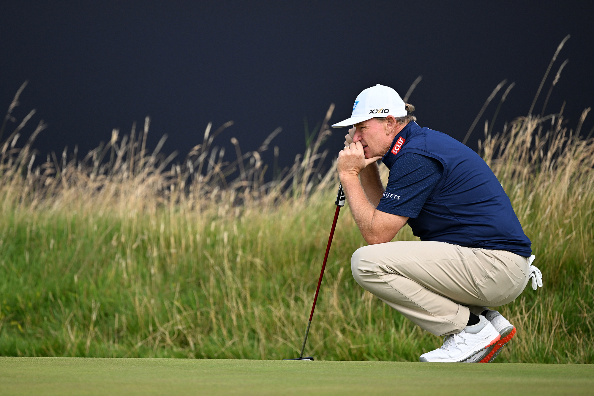 Ernie Els reading a putt on the green at the Open Championship, crouching down to see the line