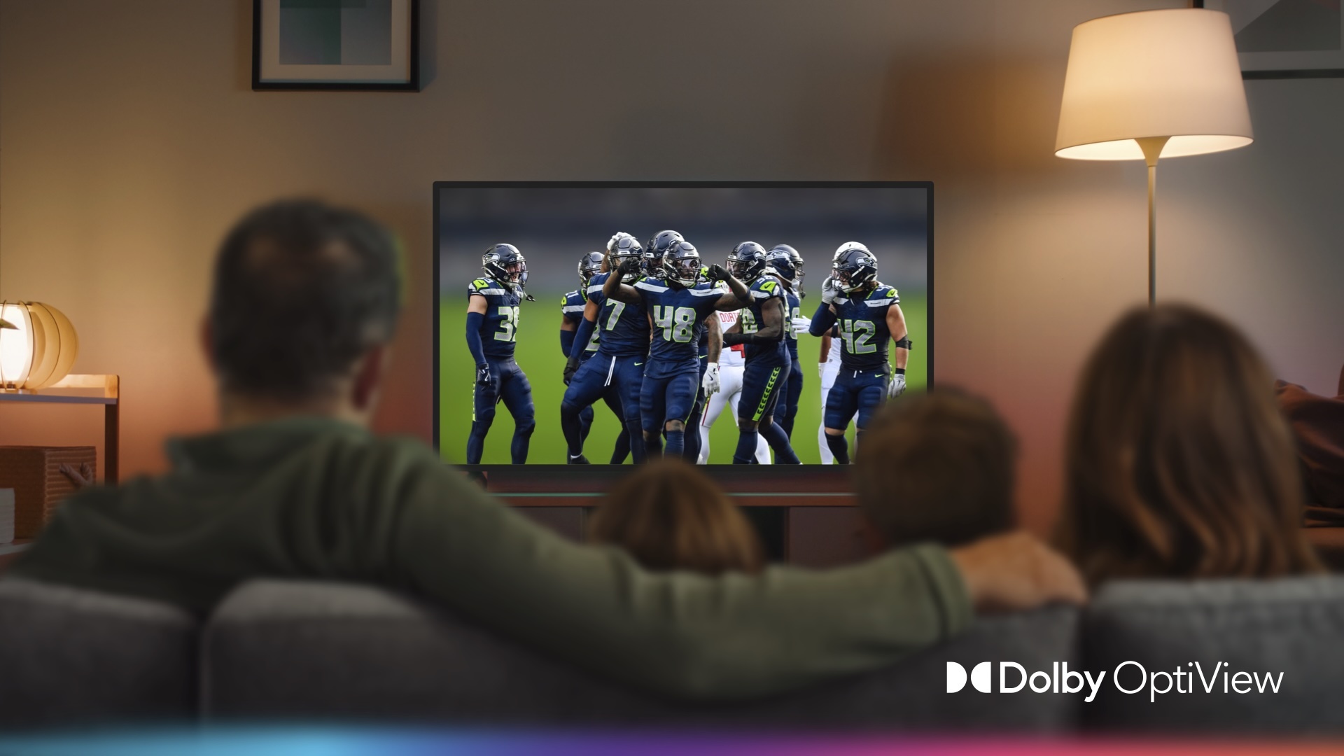 Shot of family watching TV showing the NFL Seahawks