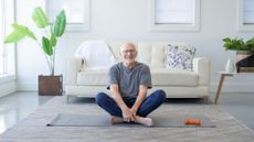 senior man sits cross-legged on yoga mat