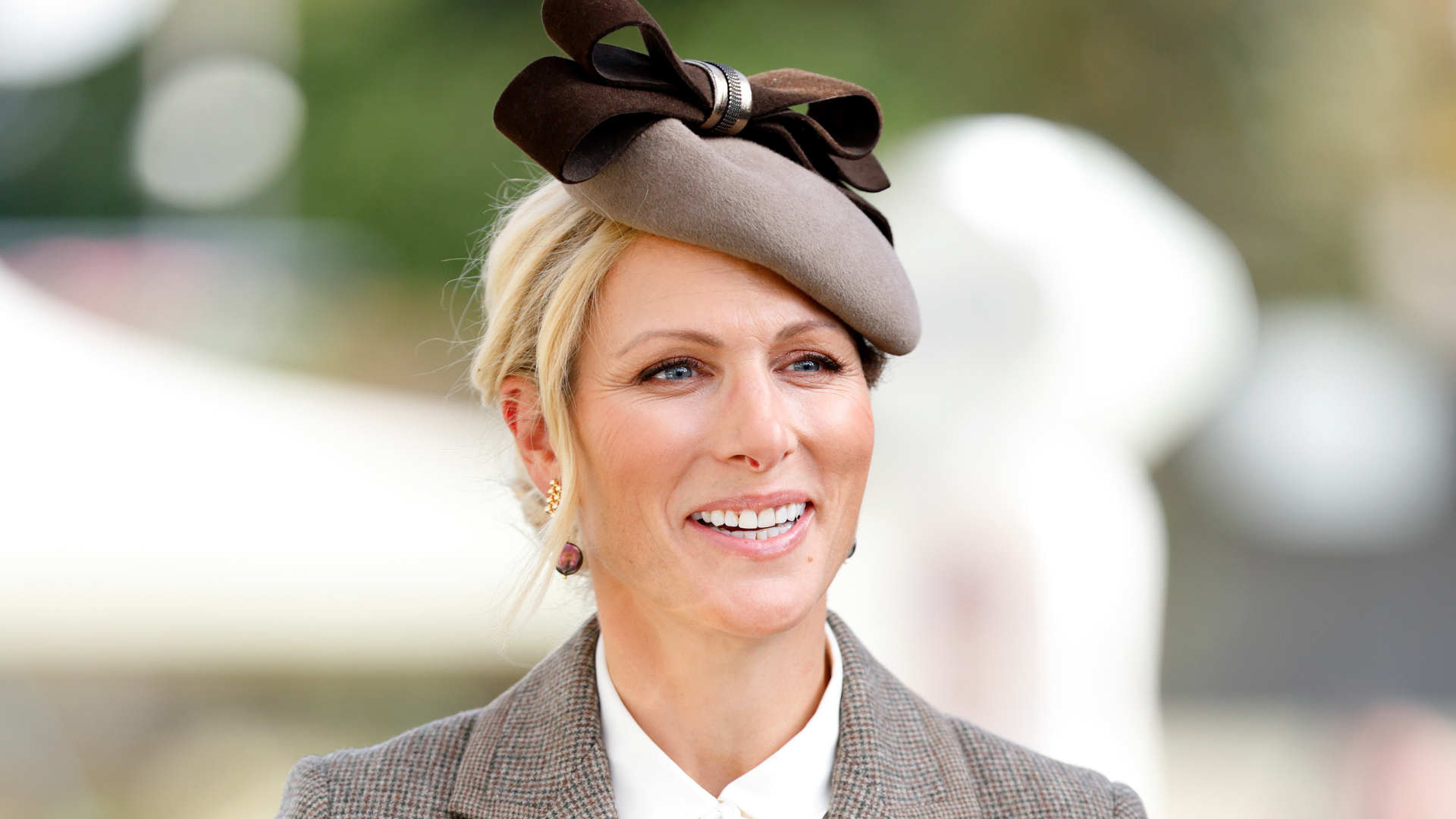 Image of Zara Tindall smiling at 2026 British Champions Day, wearing brown fascinator and with blonde hair in an updo 