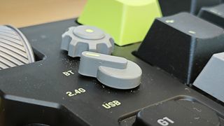 A black and green NuPhy Field75 keyboard on a wooden desk