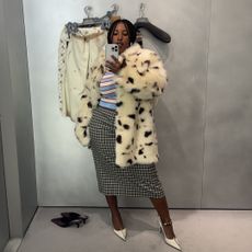 Mecca James-Williams in a white fur coat, blue and white striped polo shirt, and black checked skirt